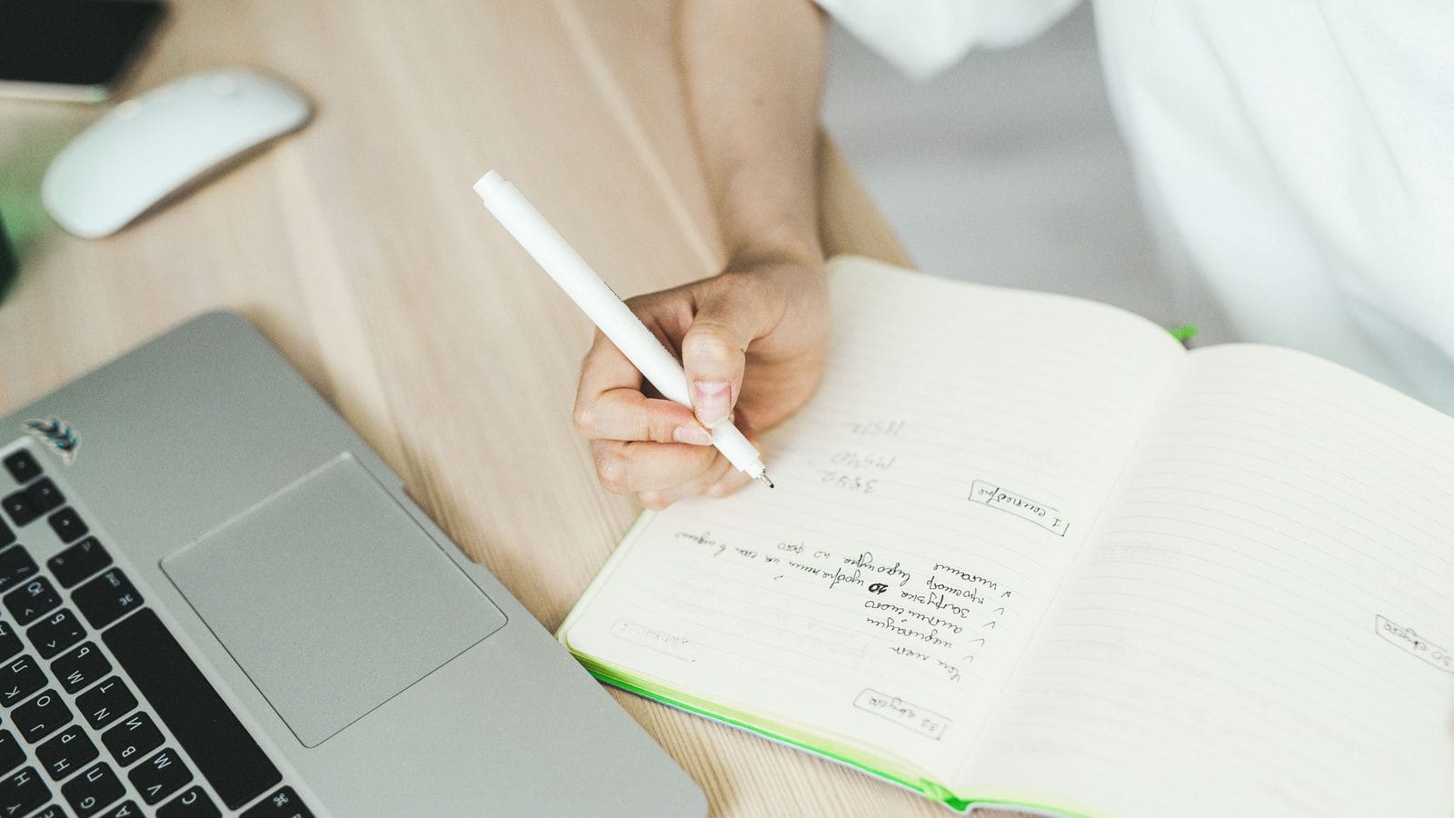 Redacción de titulares en un cuaderno junto a un ordenador